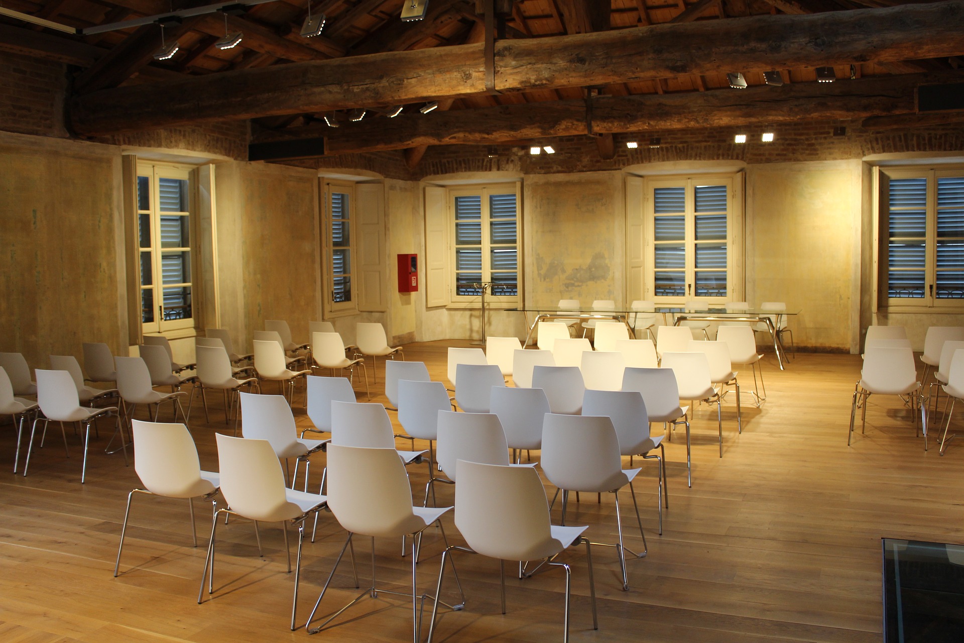 A room with many white chairs and wooden floors
